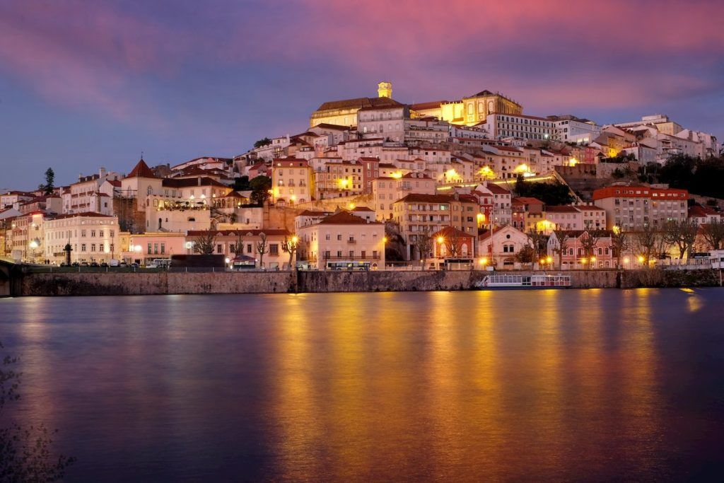 What to see in Portugal: Coimbra buildings seen from the river at dusk