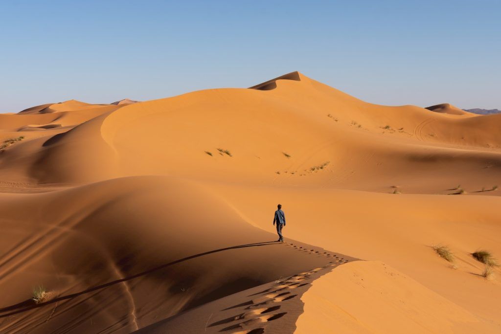 Man walking on golden Sahara dunes in Morocco