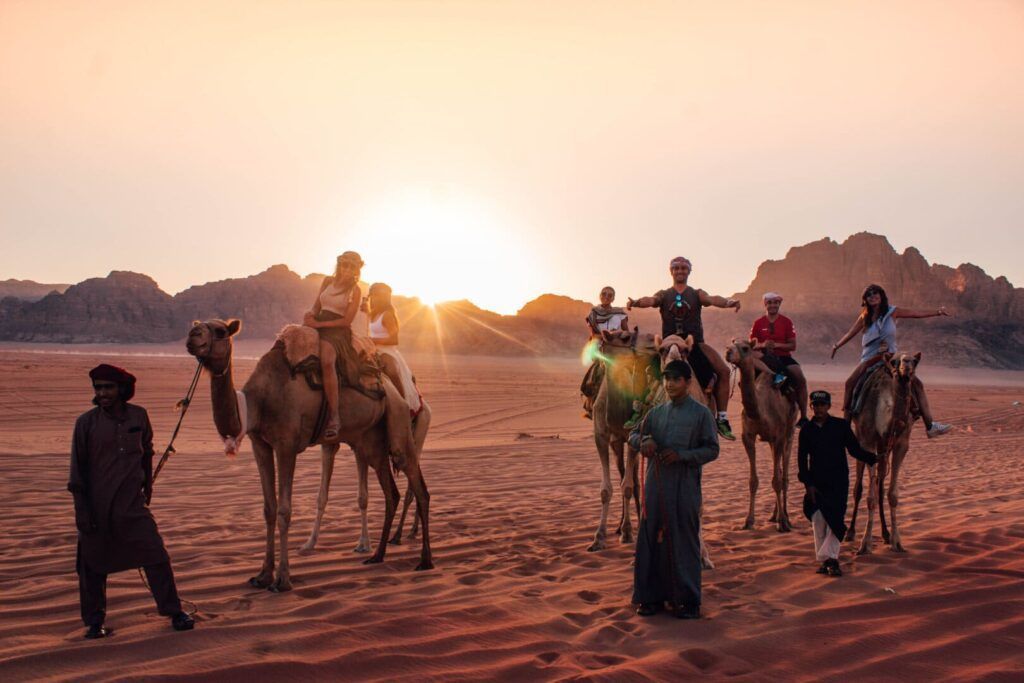 desert bright red rocks ochre sand and people on camels