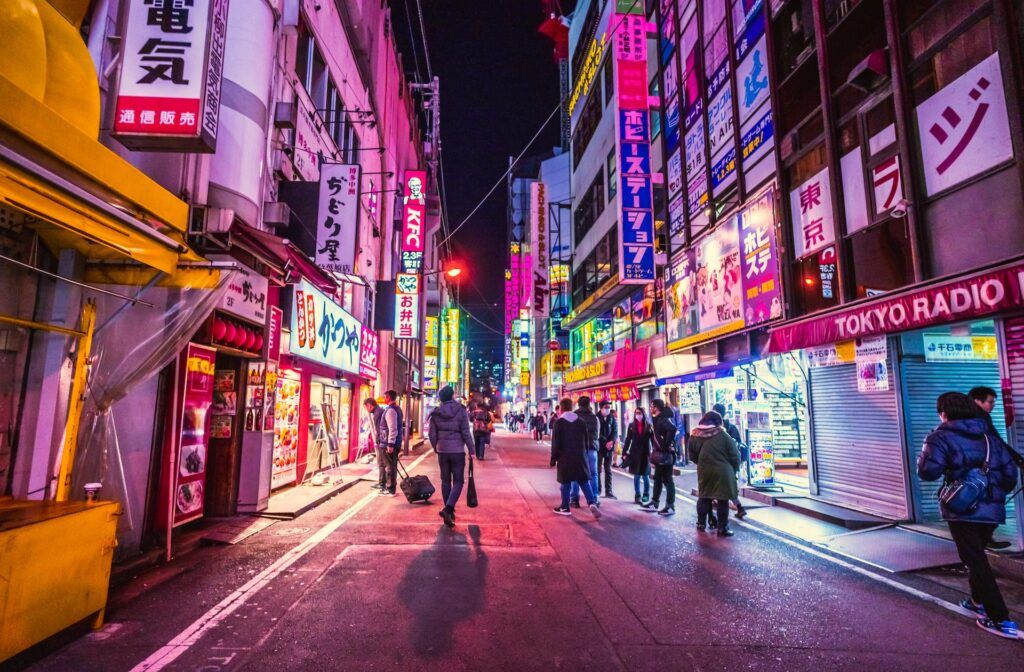 people walk in a street full of neon lights in Akihabara