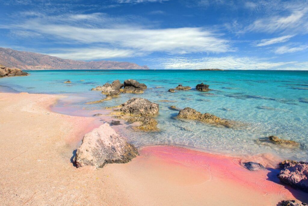 pink and brown sand with grey rocks and turquoise sea