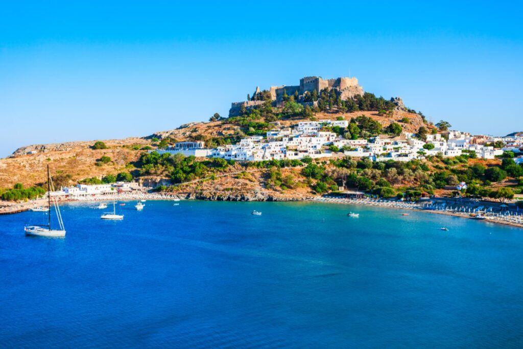 a castle and small houses perched on a promontory in the afternoon