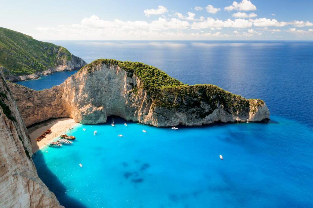 brown and green rocks surrounded by blue sea