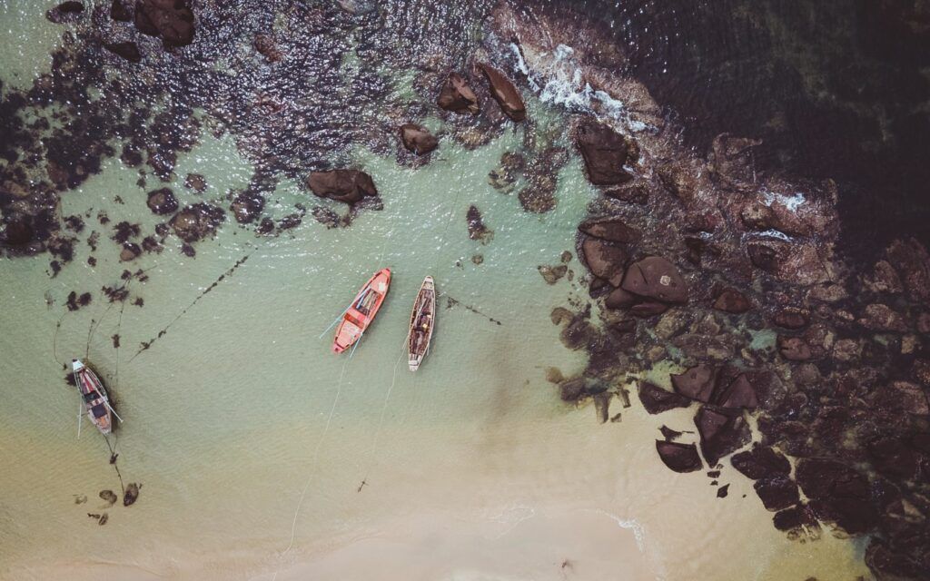 two boats in the sea and brown rocks
