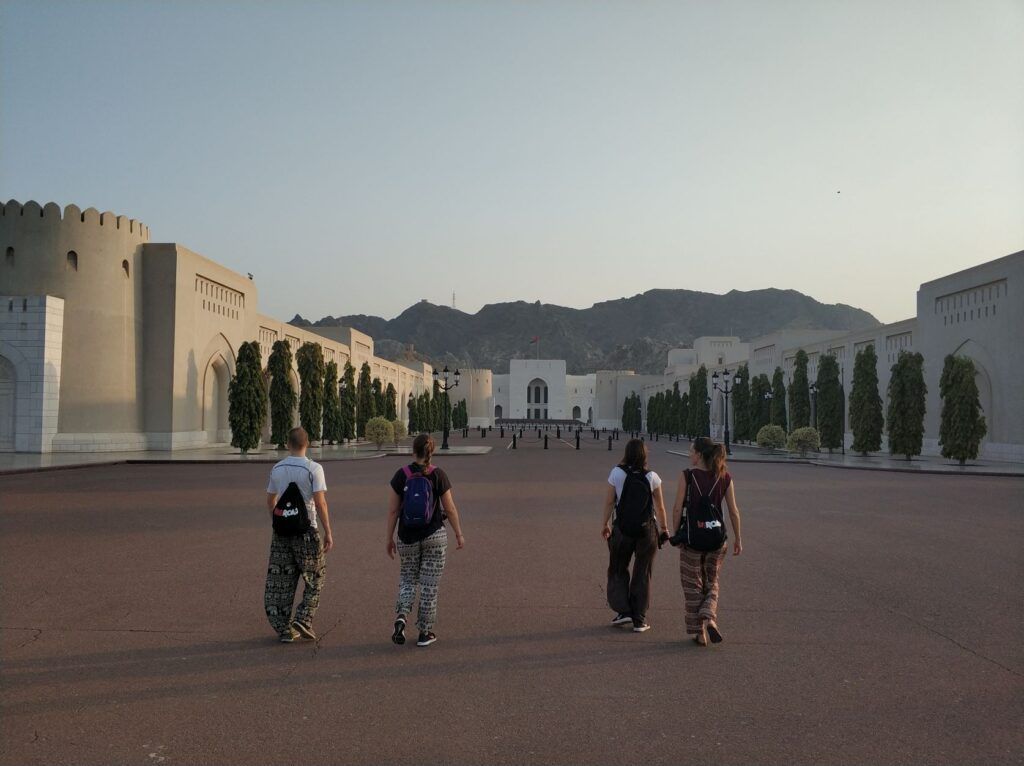 People walk among ancient buildings in Oman at sunset