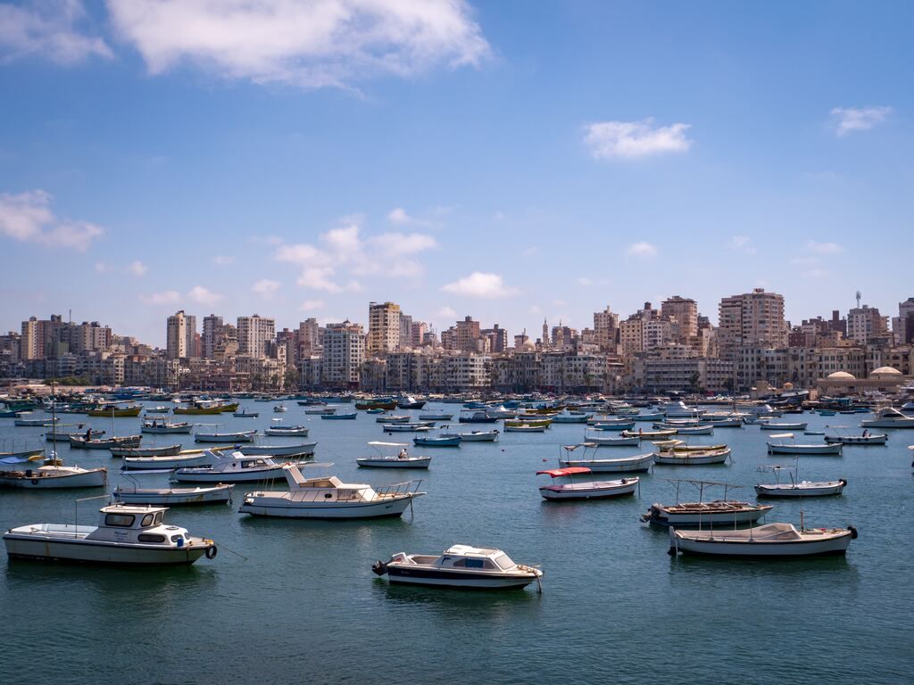 Boats on the sea near the city buildings under the blue sky during the day.