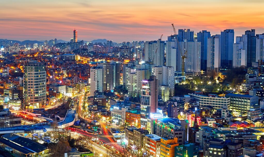 Aerial photograph of skyscrapers illuminated at dawn in Seoul.