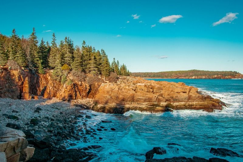 Waves crashing against pink granite cliffs along the rugged Atlantic coastline in Acadia National Park