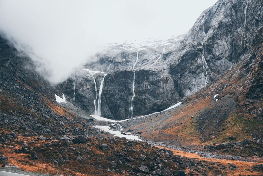 Grey rocky mountain under a white sky during the day in Fiordland National Park