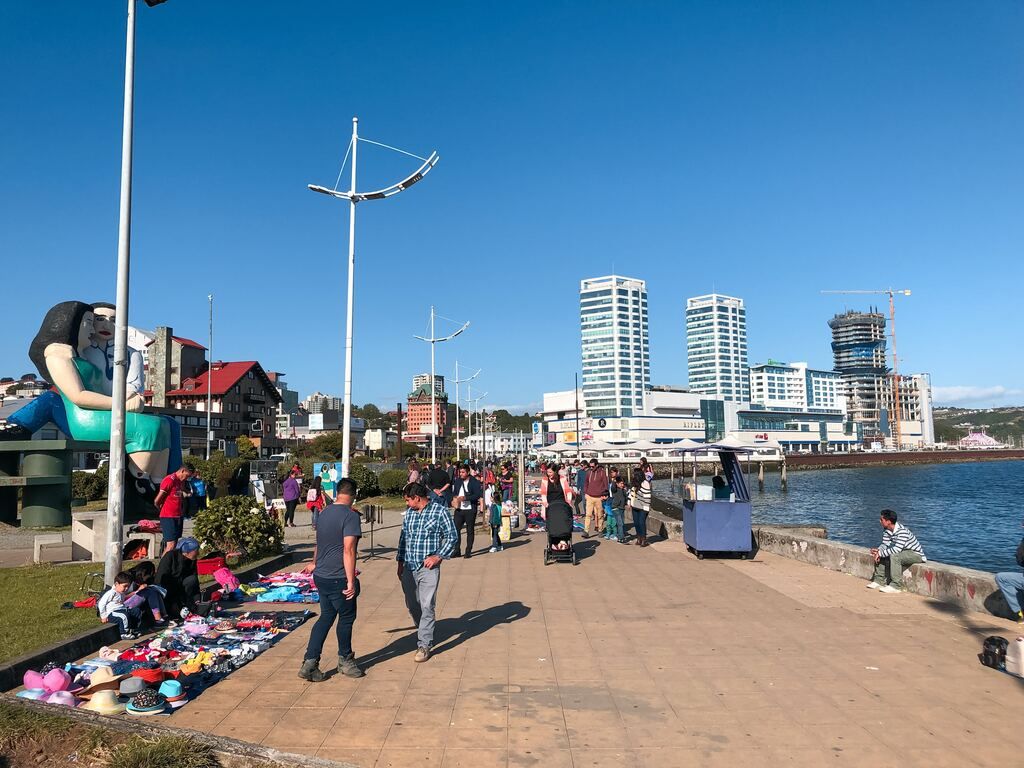 A group of people walking along a pavement near a body of water