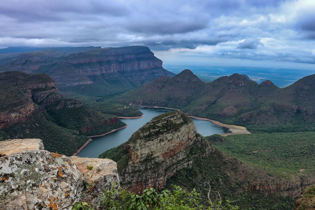 Body of water and green mountain under the blue sky.