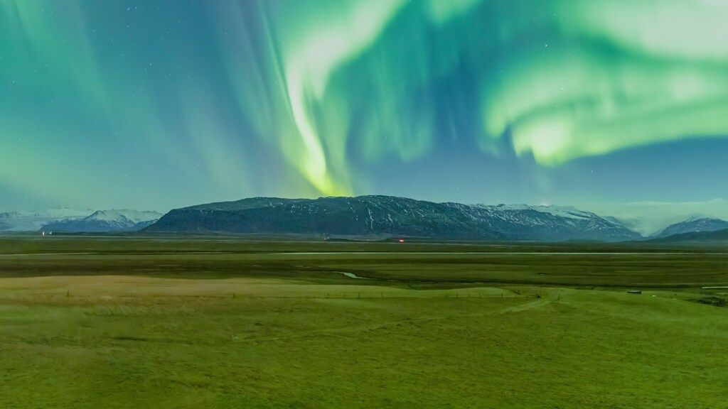 A green field with a mountain in the background.