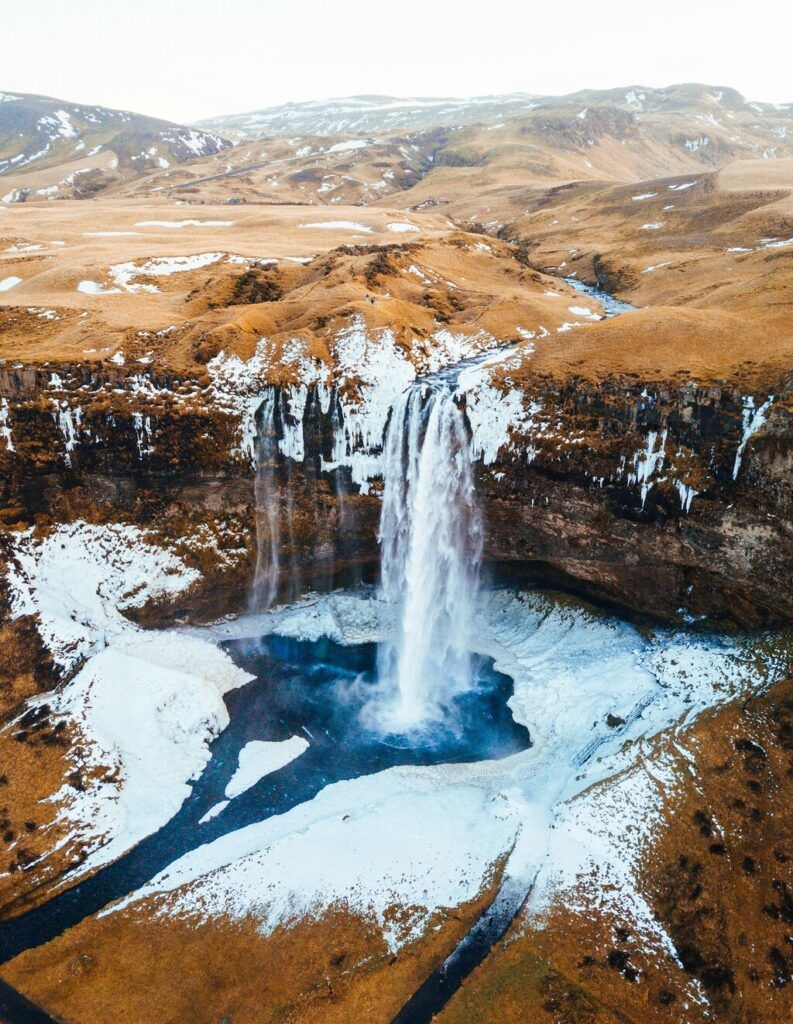 Aerial photograph of waterfalls near mountains during the day.