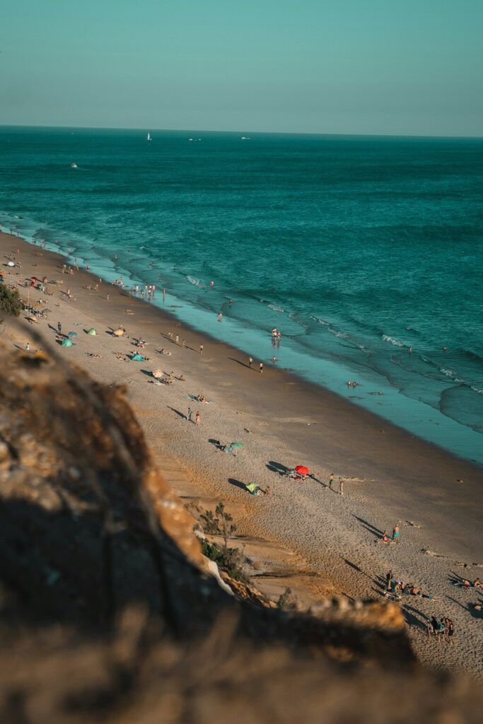 a group of people standing on top of a sandy beach in Portugal