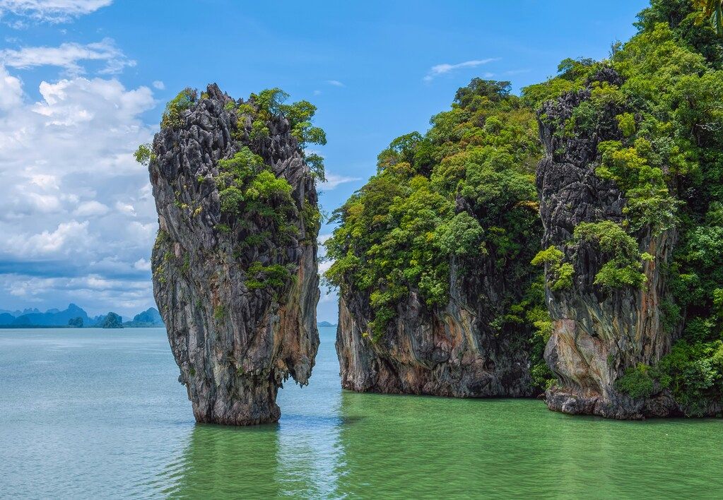 green and brown rock formation on the blue sea under the blue sky during the day