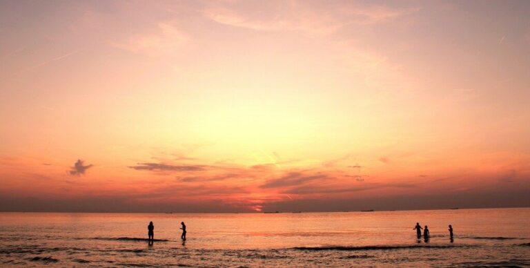 People enjoying a beautiful sunset on a beach with calm waters