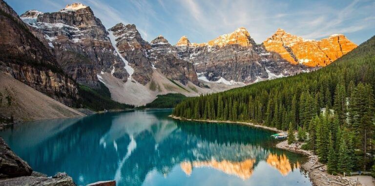 The stunning Moraine Lake in Canada, featuring turquoise waters reflecting the snow-capped Rocky Mountains and a dense pine forest.