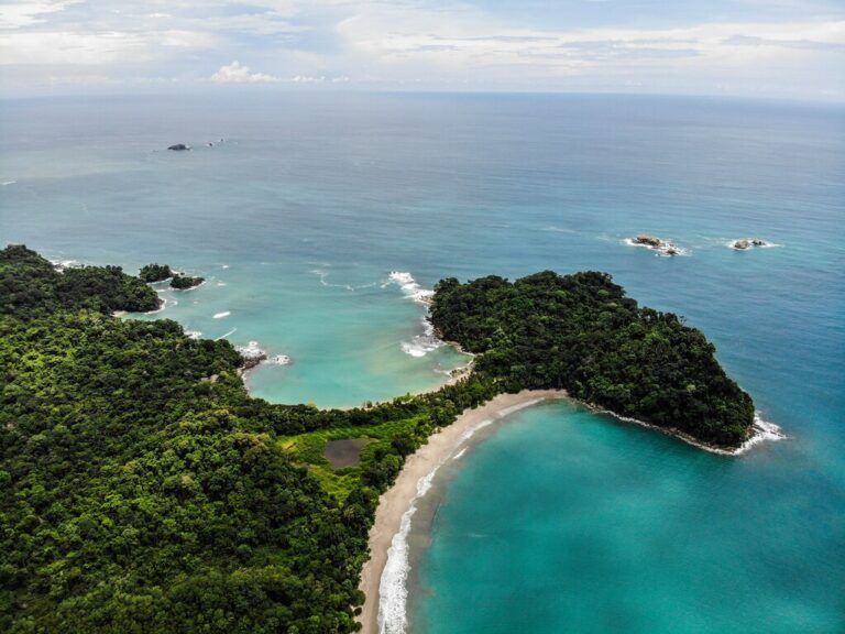 Aerial view of lush green rainforest and turquoise waters on the coastline of Costa Rica.