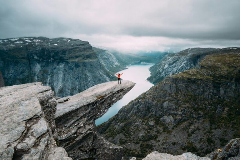 A person standing triumphantly on the edge of Trolltunga in Norway