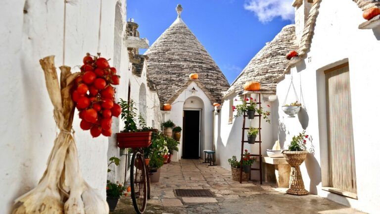 Narrow stone alley between whitewashed Trulli houses with their cone-shaped roofs.