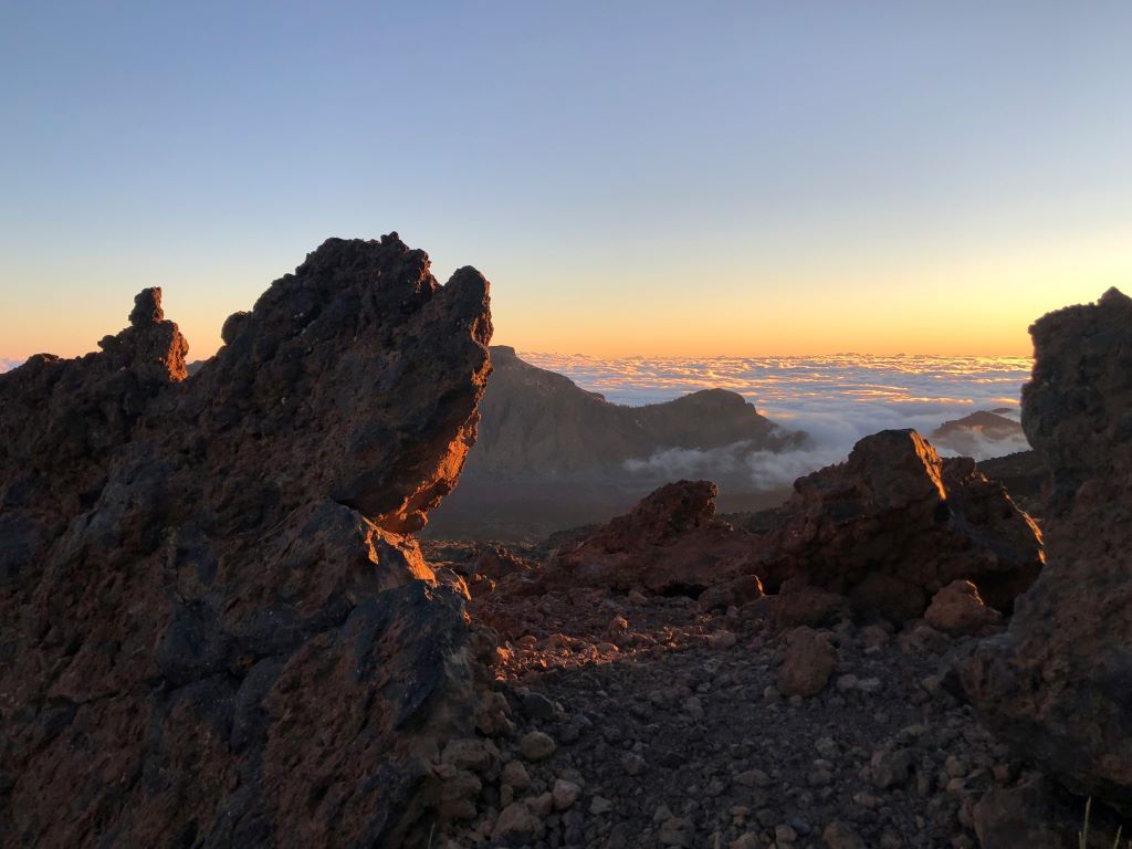 Rugged volcanic rock formations at sunset overlooking a sea of clouds in Mount Teide National Park, Tenerife