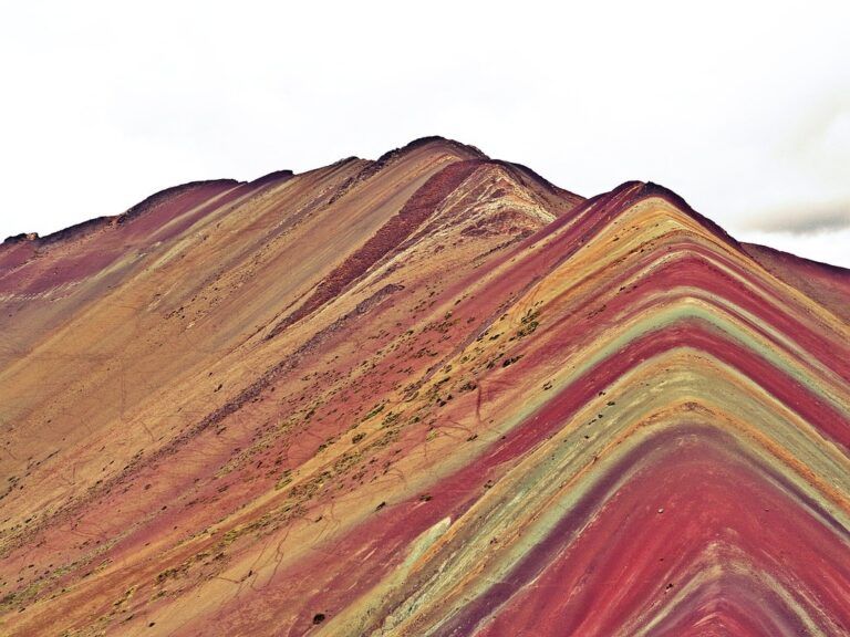 Rainbow Mountain in Peru showing vibrant stripes of red, gold, and green.