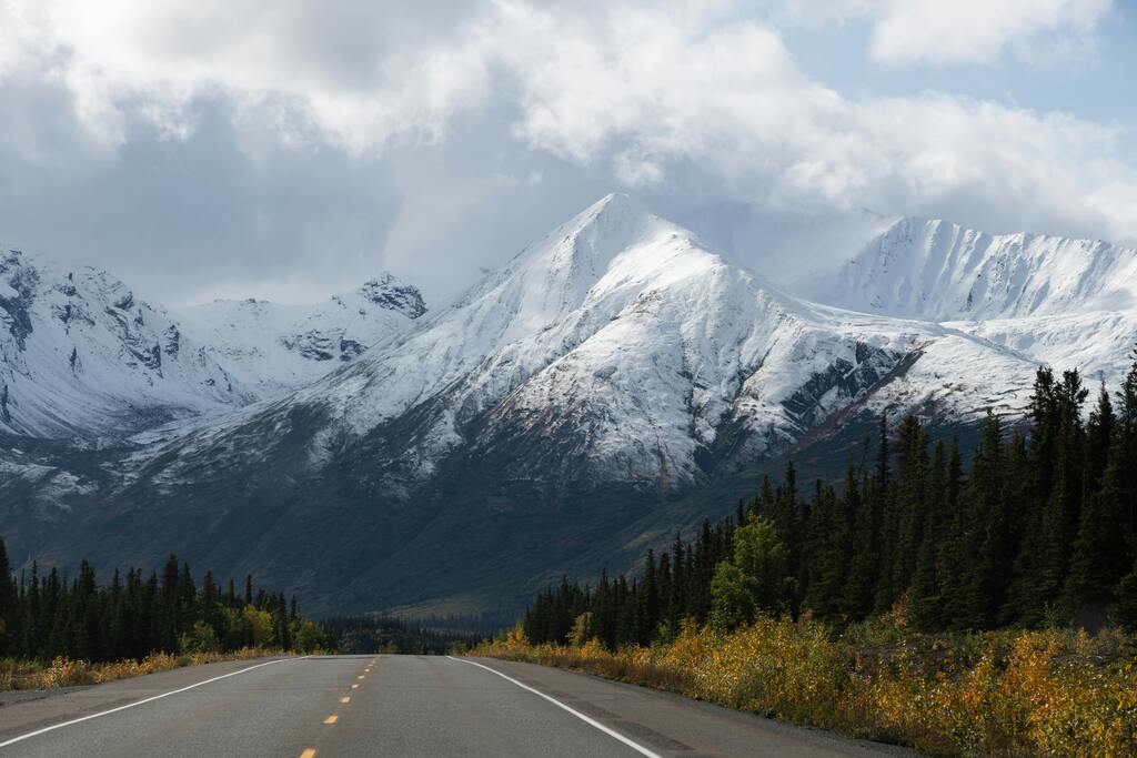Alaskan Highway: A scenic road leading through snowy mountains and lush forests in Alaska.

