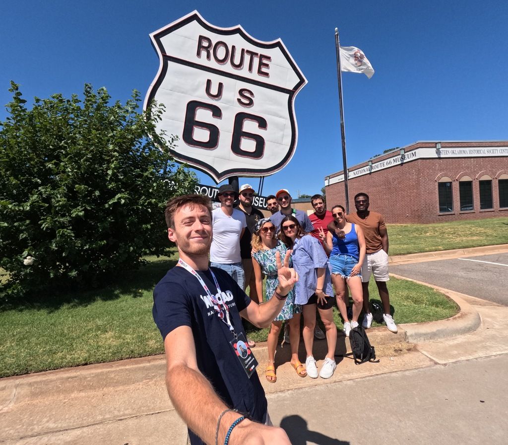 A group of travelers posing for a selfie in front of the Route 66 sign during a WeRoad group trip in the USA.