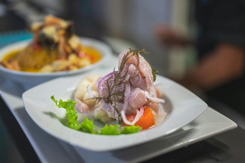 Ceviche dish in a Peruvian restaurant, served with fresh onions, lettuce, and sweet potato.