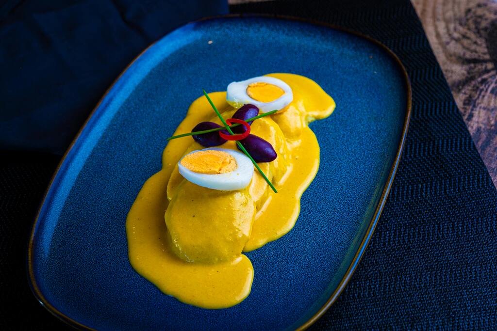 Papa a la huancaína, Peruvian boiled potatoes covered in a creamy yellow pepper sauce, garnished with boiled eggs and olives.
