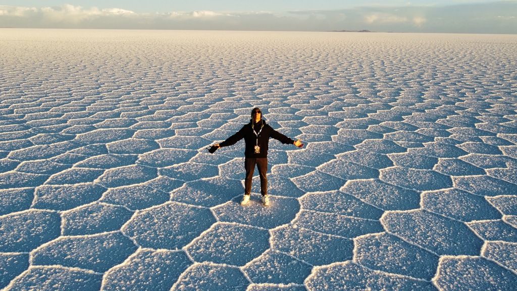 A person standing in the middle of the endless hexagonal salt formations at Salar de Uyuni, Bolivia.