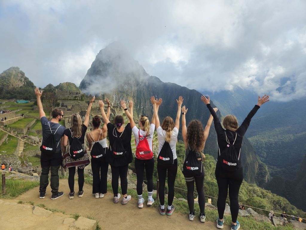 WeRoad group raising arms at Machu Picchu.
