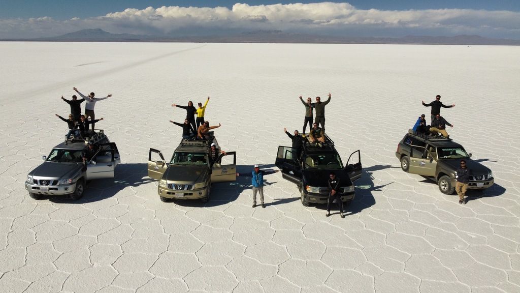 Travelers standing on top of off-road vehicles, celebrating their journey across the salt flats.