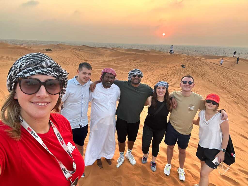 WeRoad group trip in Dubai desert at sunset with local guide and traditional headscarves