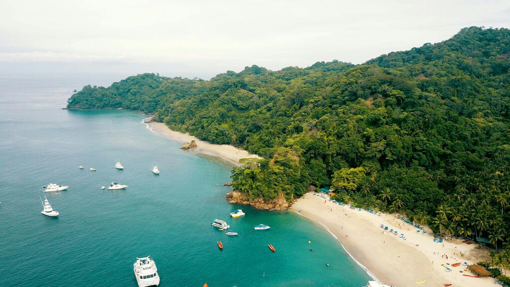Aerial view of a white sand beach, turquoise water, and dense tropical jungle in Costa Rica.