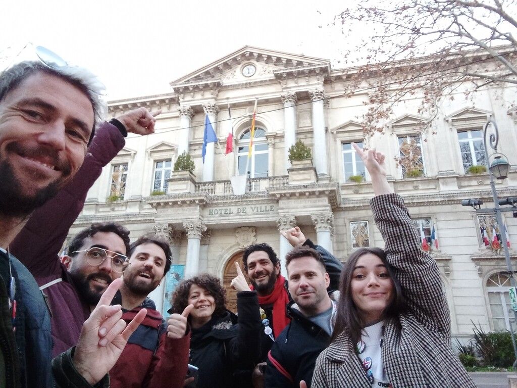 A group of happy travelers posing in front of the Hôtel de Ville in France during a WeRoad trip.