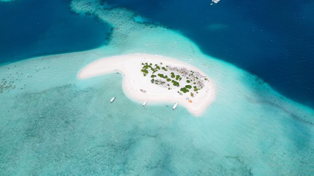 Aerial view of a Maldive island with white sand and turquoise water, perfect for an exotic getaway.