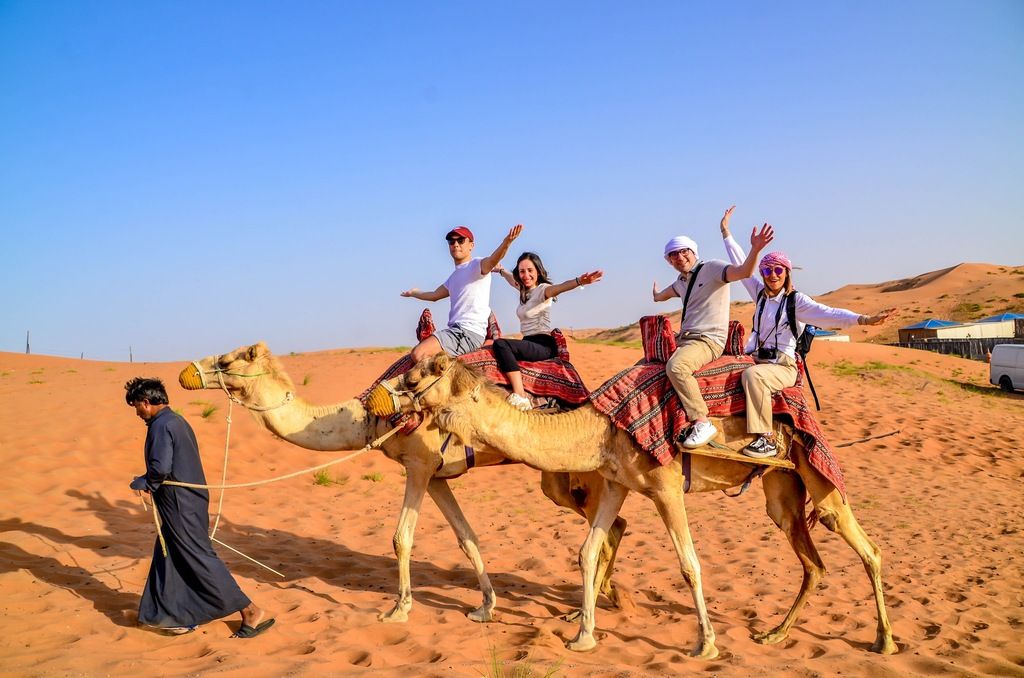 Tourists enjoying a camel ride in the Dubai desert with a local guide