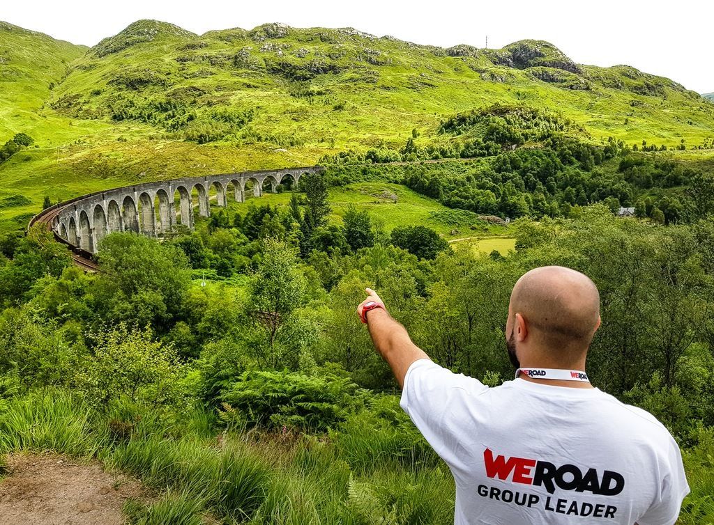 WeRoad group leader pointing at Glenfinnan Viaduct in the Scottish Highlands, Scotland
