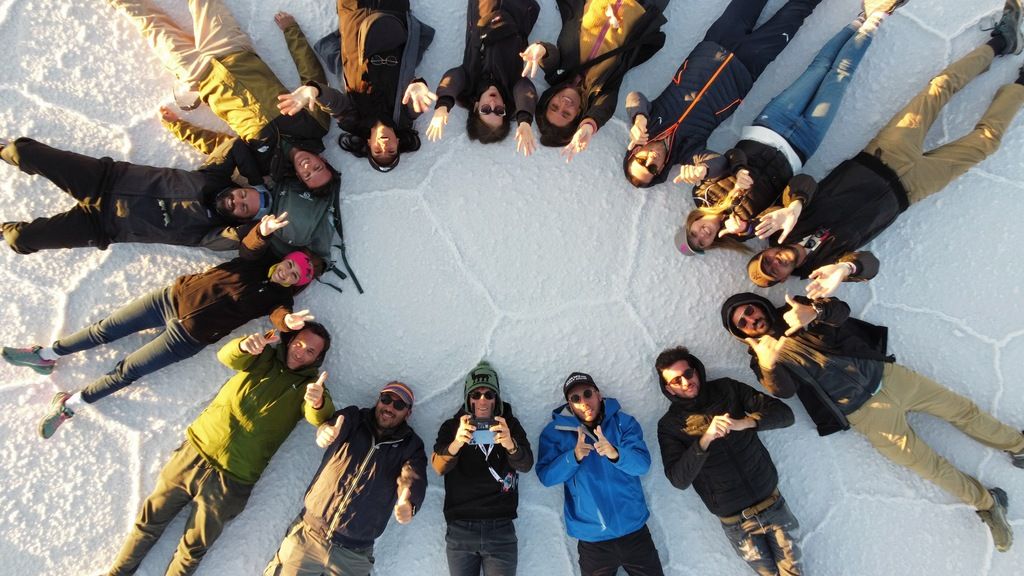 WeRoad group lying in a circle on the Uyuni Salt Flats, Bolivia.