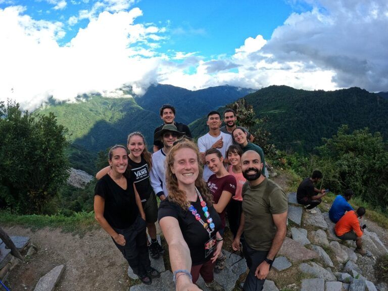 A group of WeRoad travelers taking a smiling selfie at a mountain viewpoint during a group trip.