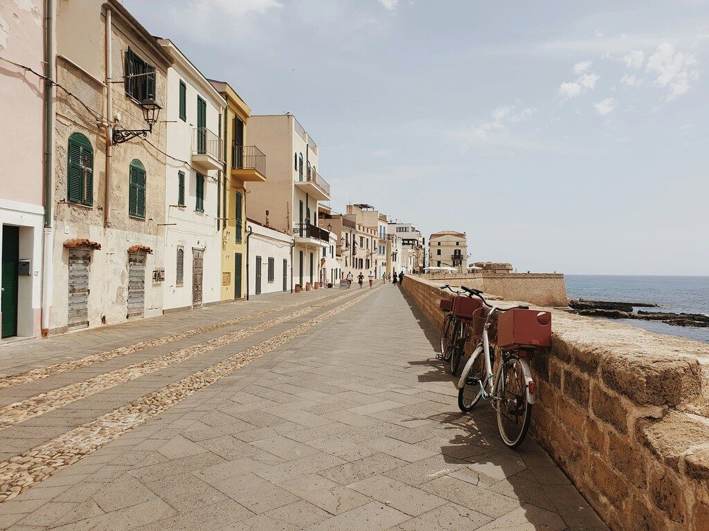 Scenic promenade with old houses and parked bicycles along the waterfront in Alghero, Sardinia