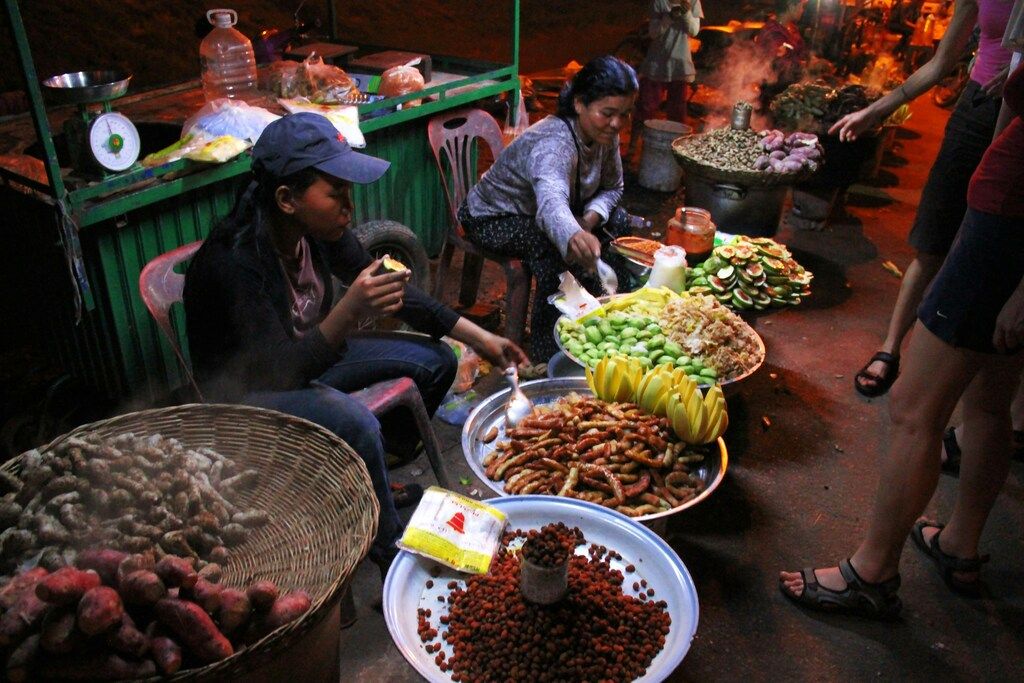 Women preparing traditional street food at a vibrant Southeast Asian night market.