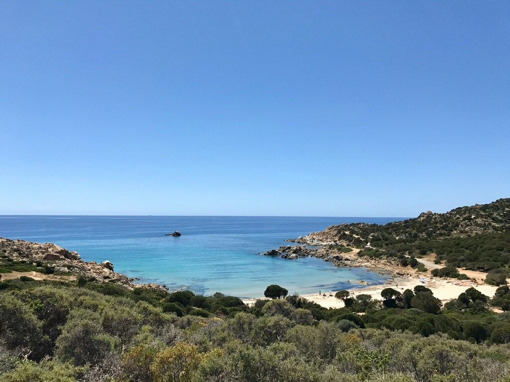 Secluded cove with crystal-clear water and rocky coastline in southern Sardinia, Italy