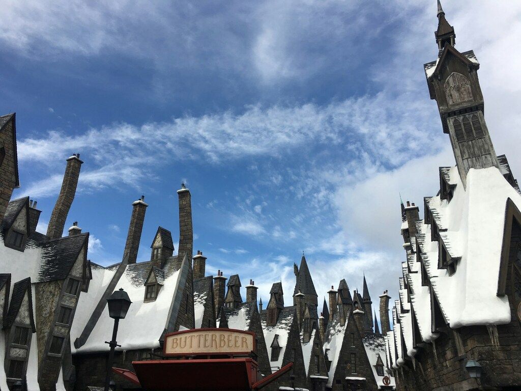 Snow-covered rooftops of Hogsmeade village with a Butterbeer stand, inspired by the Harry Potter universe