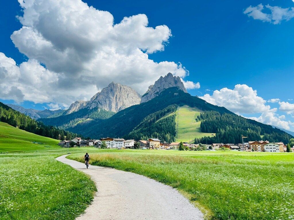 Cyclist riding along a scenic path towards the mountains in the Dolomites, Italy