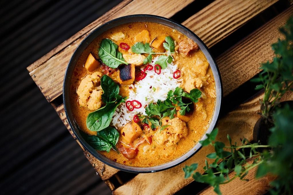 Colorful bowl of Southeast Asian Khmer Red Curry with rice, vegetables, chili and herbs.