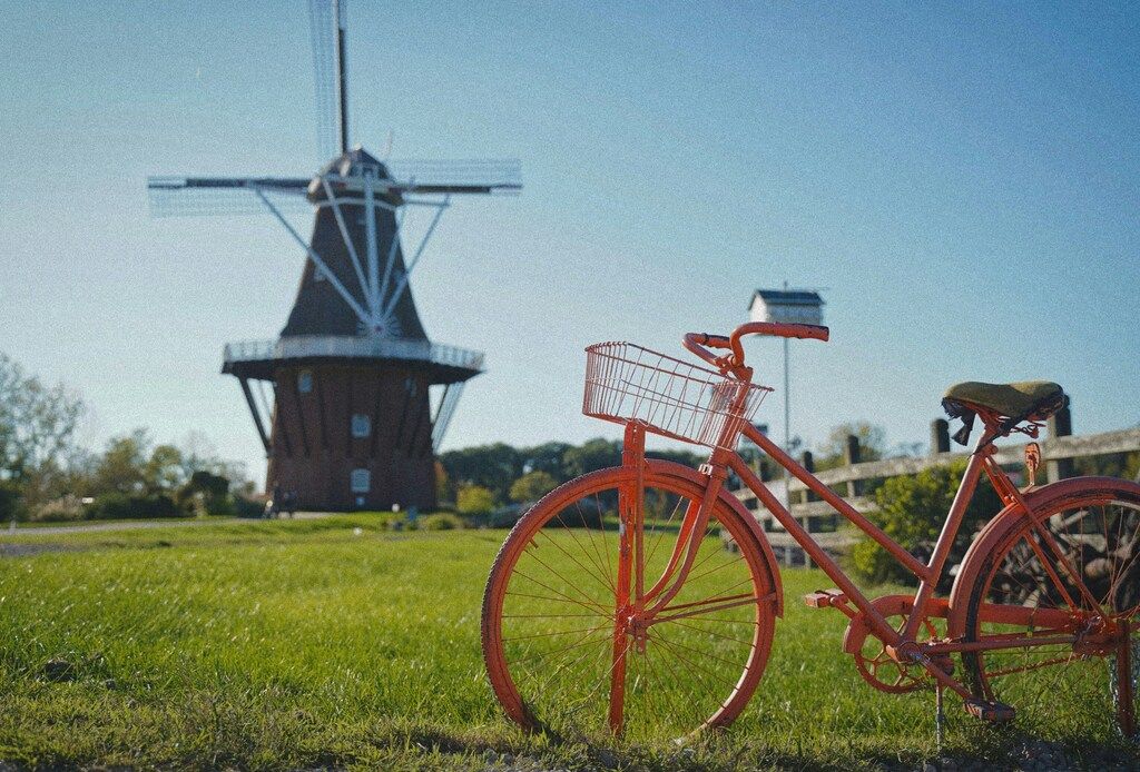 Orange bicycle with a basket parked in front of a traditional windmill