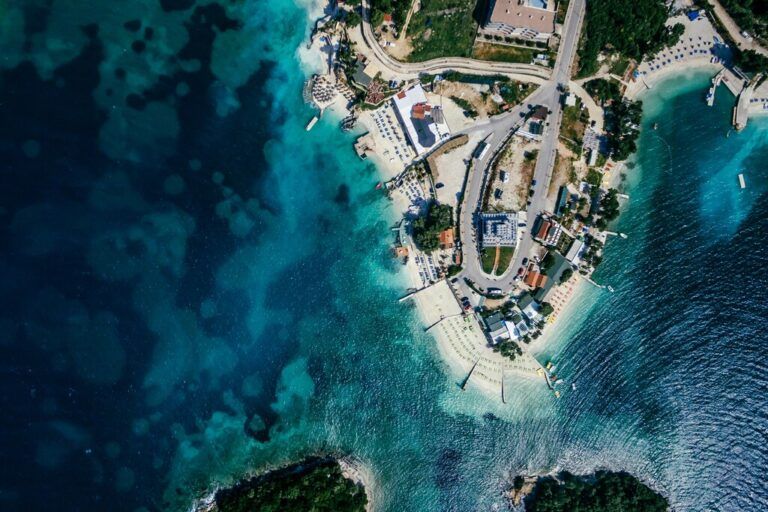 Aerial view of the Albanian Riviera coastline showing turquoise water, white sandy beaches, and coastal development.