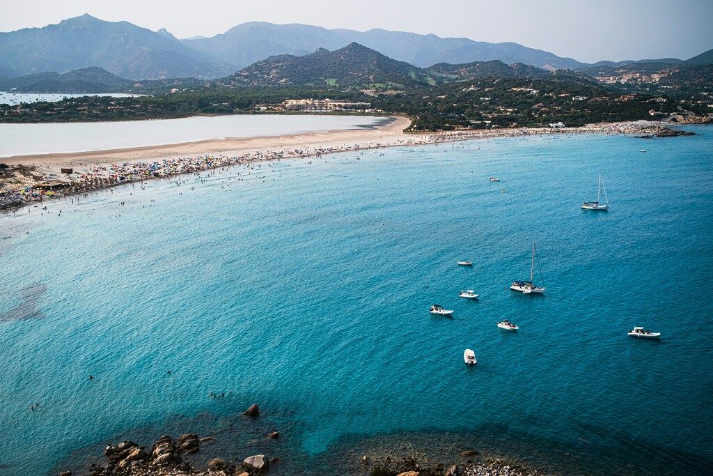 Aerial view of Porto Giunco beach with turquoise waters and sailing boats in Villasimius, Sardinia